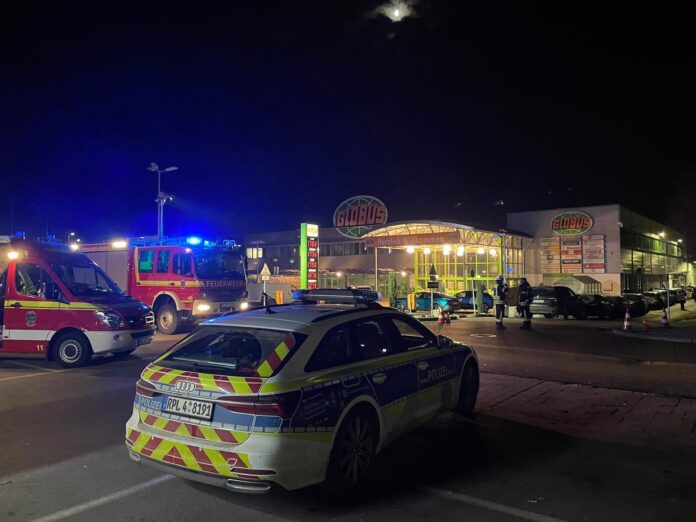 Das Foto zeigt ein Polizeiauto bei Nacht vor einem Supermarkt